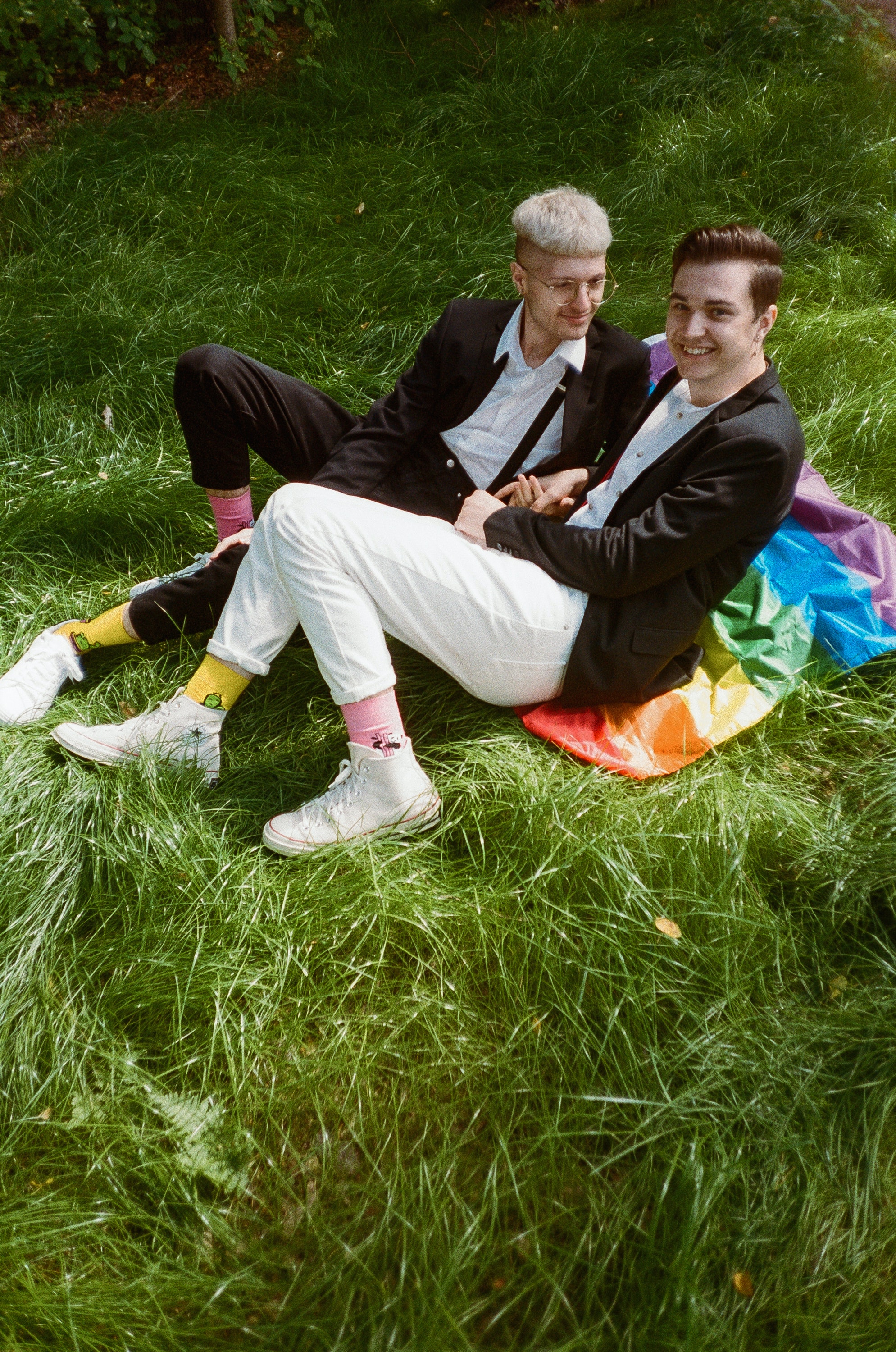 Two males on grass with rainbow flag
