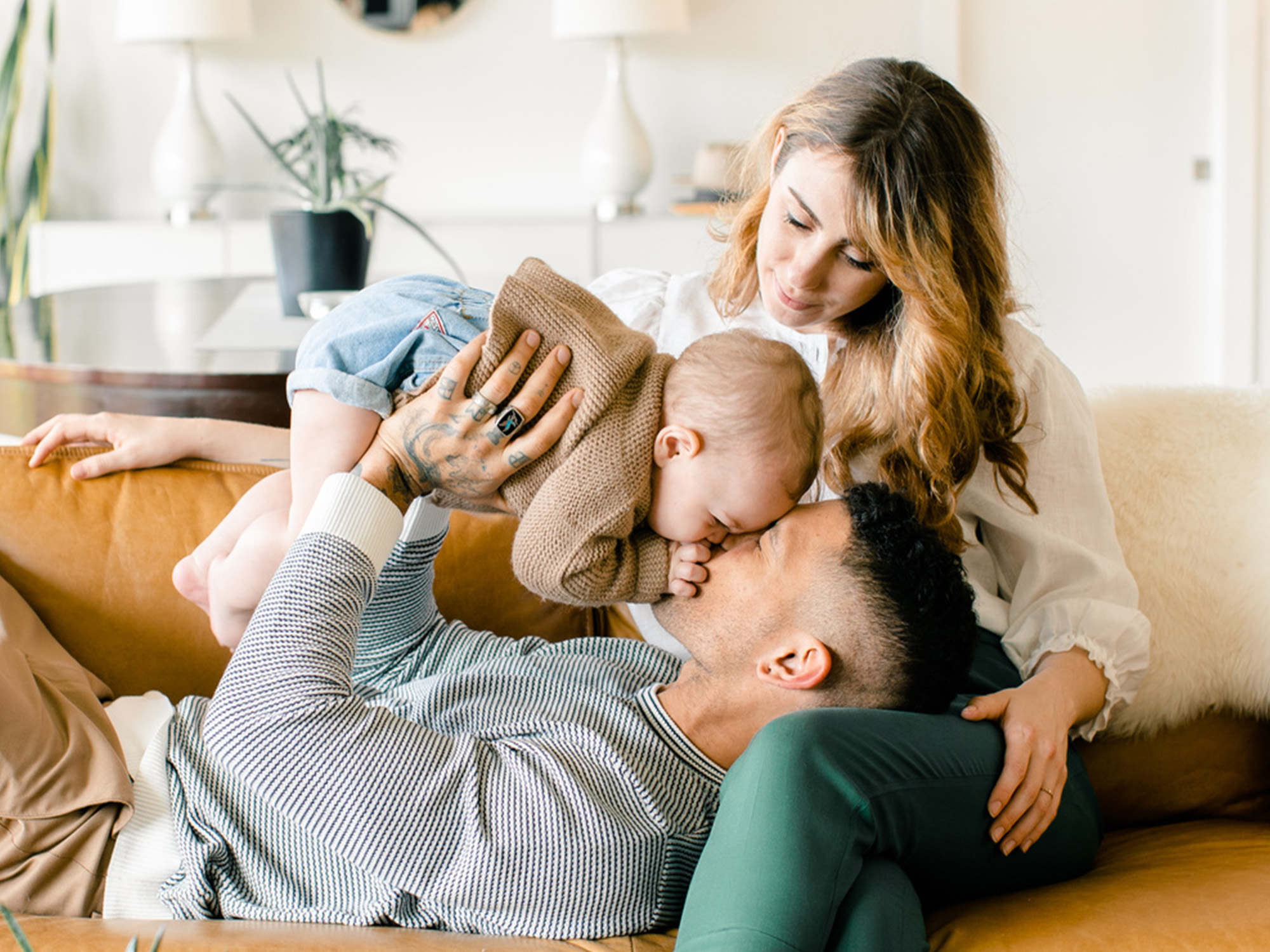 Hispanic family lounging on the couch holding their newborn baby