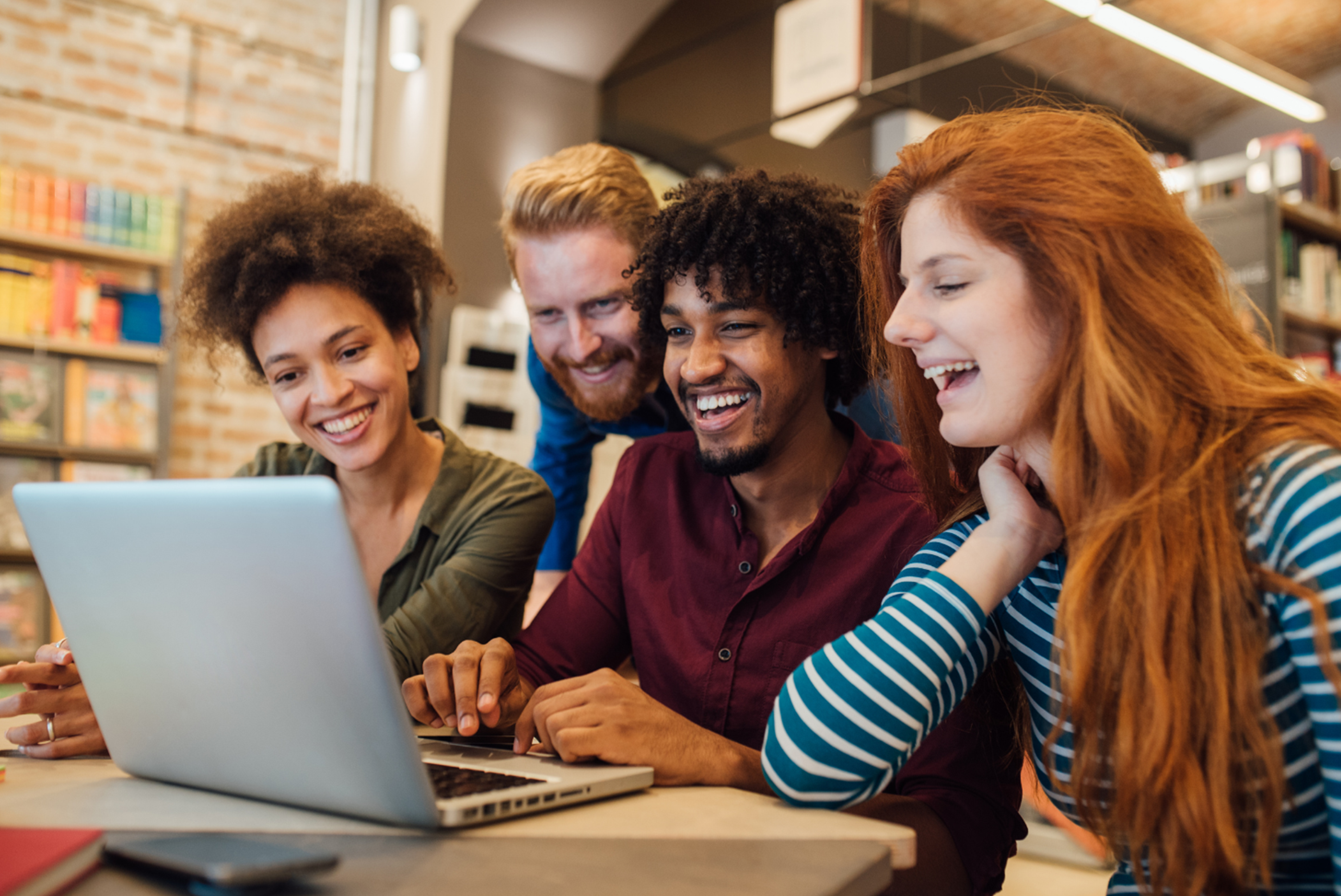 People around a laptop in a library or office setting.