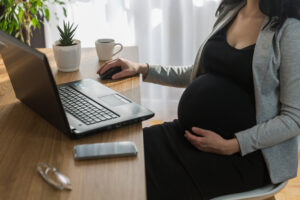 Pregnant woman is working on computer laptop and mobile phone, business.