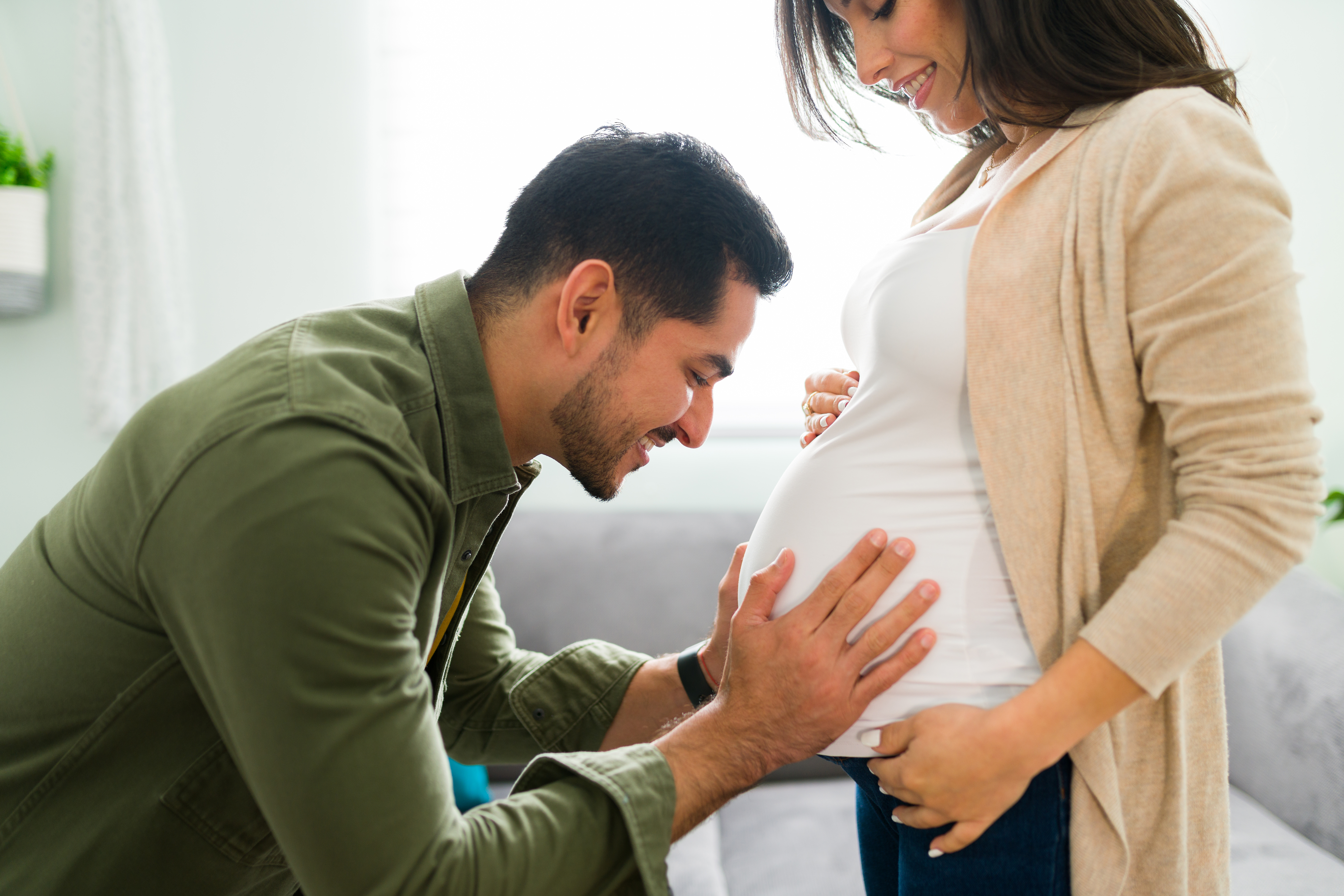 Handsome man putting face close to her wife's belly