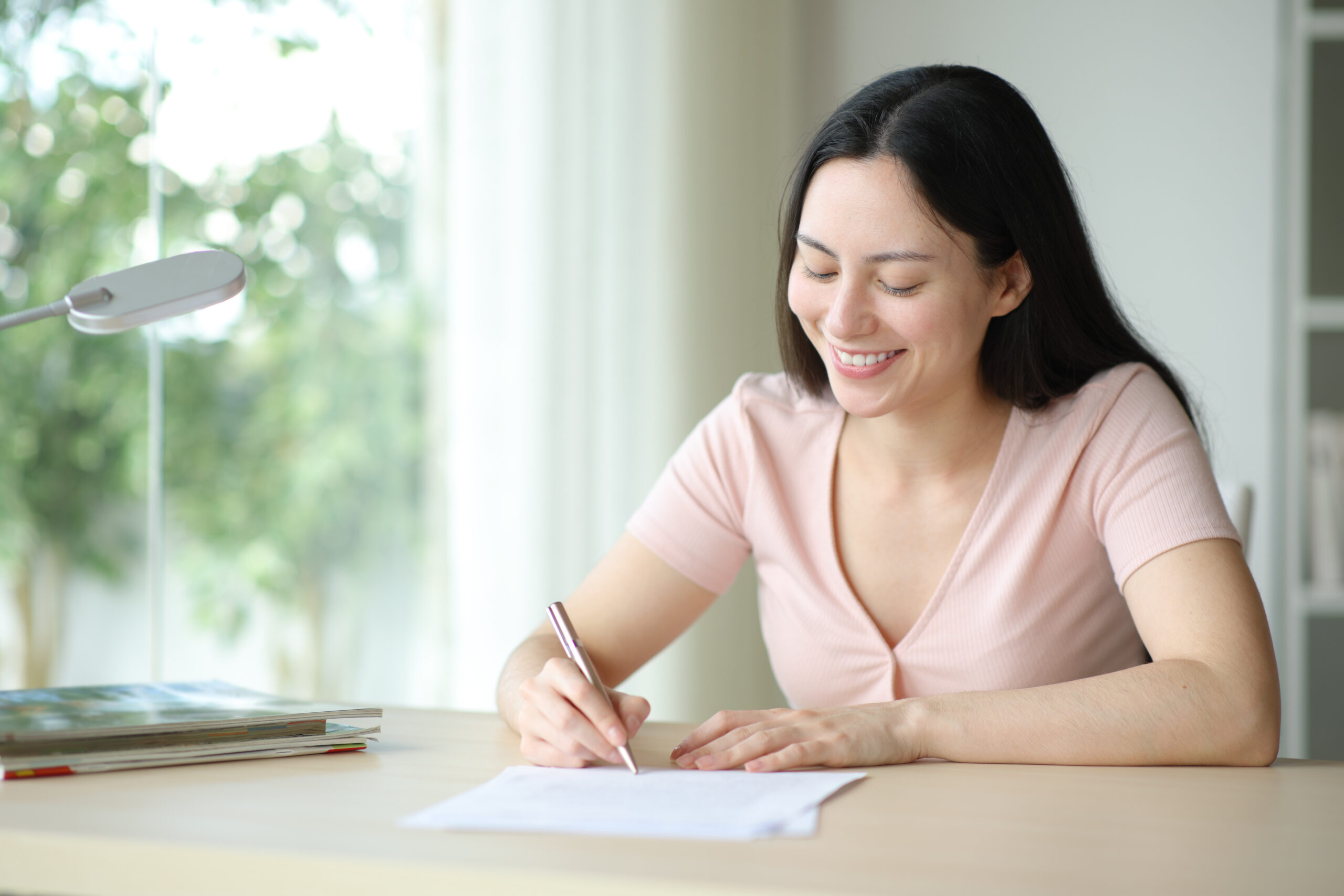 Happy asian woman signing paper in a room at home